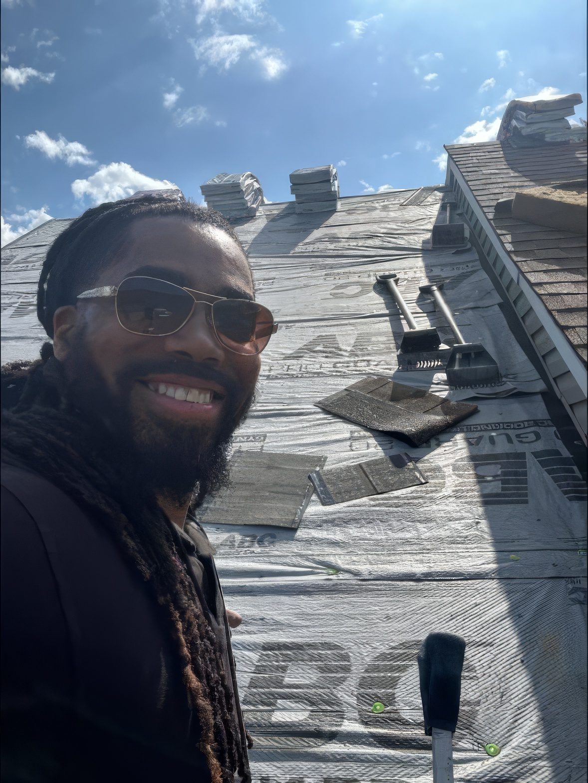 Deonta on the roof, synthetic underlayment down, bundles staged along the ridge