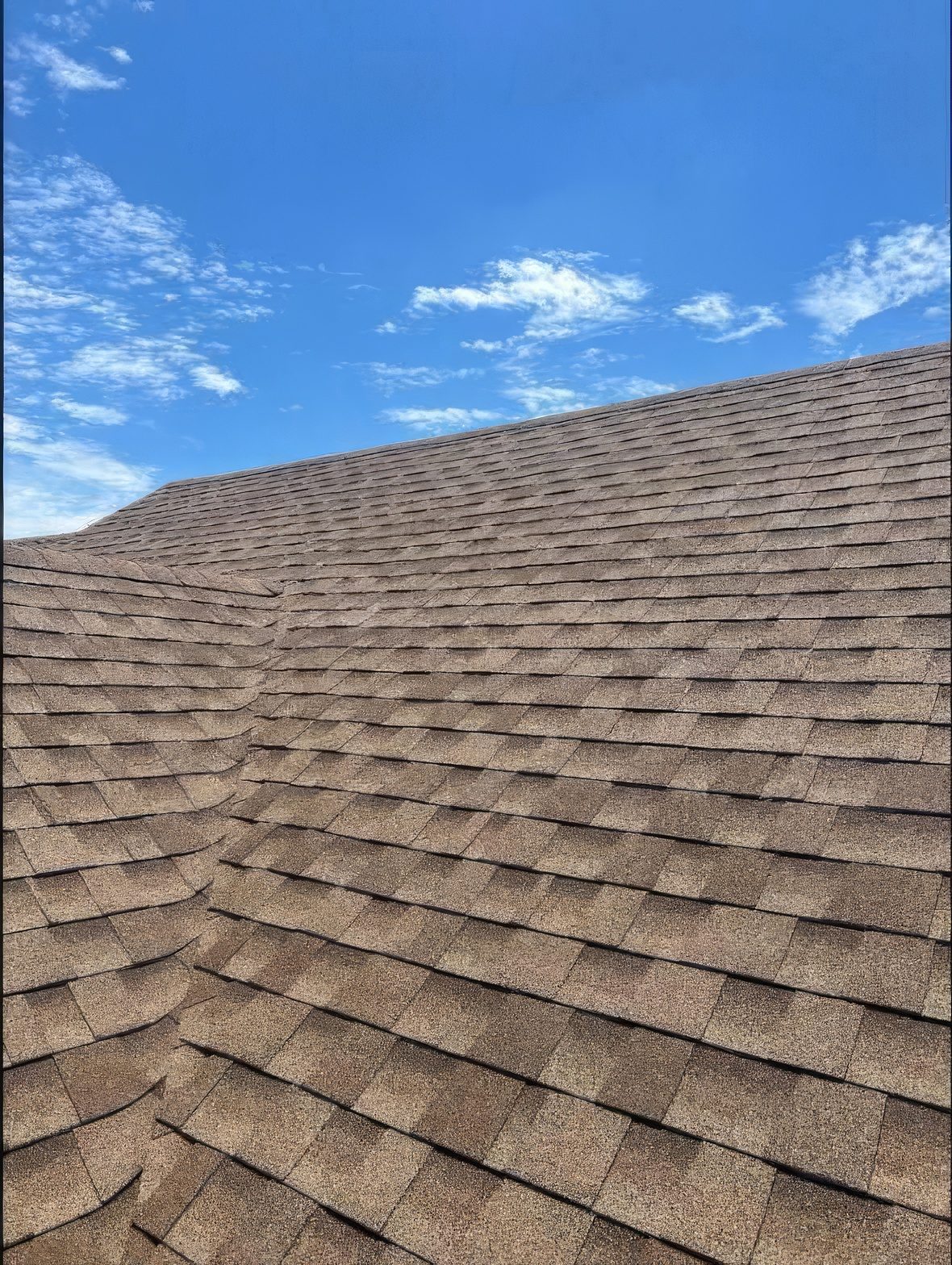 A finished roof, the valley cut clean, against a blue sky